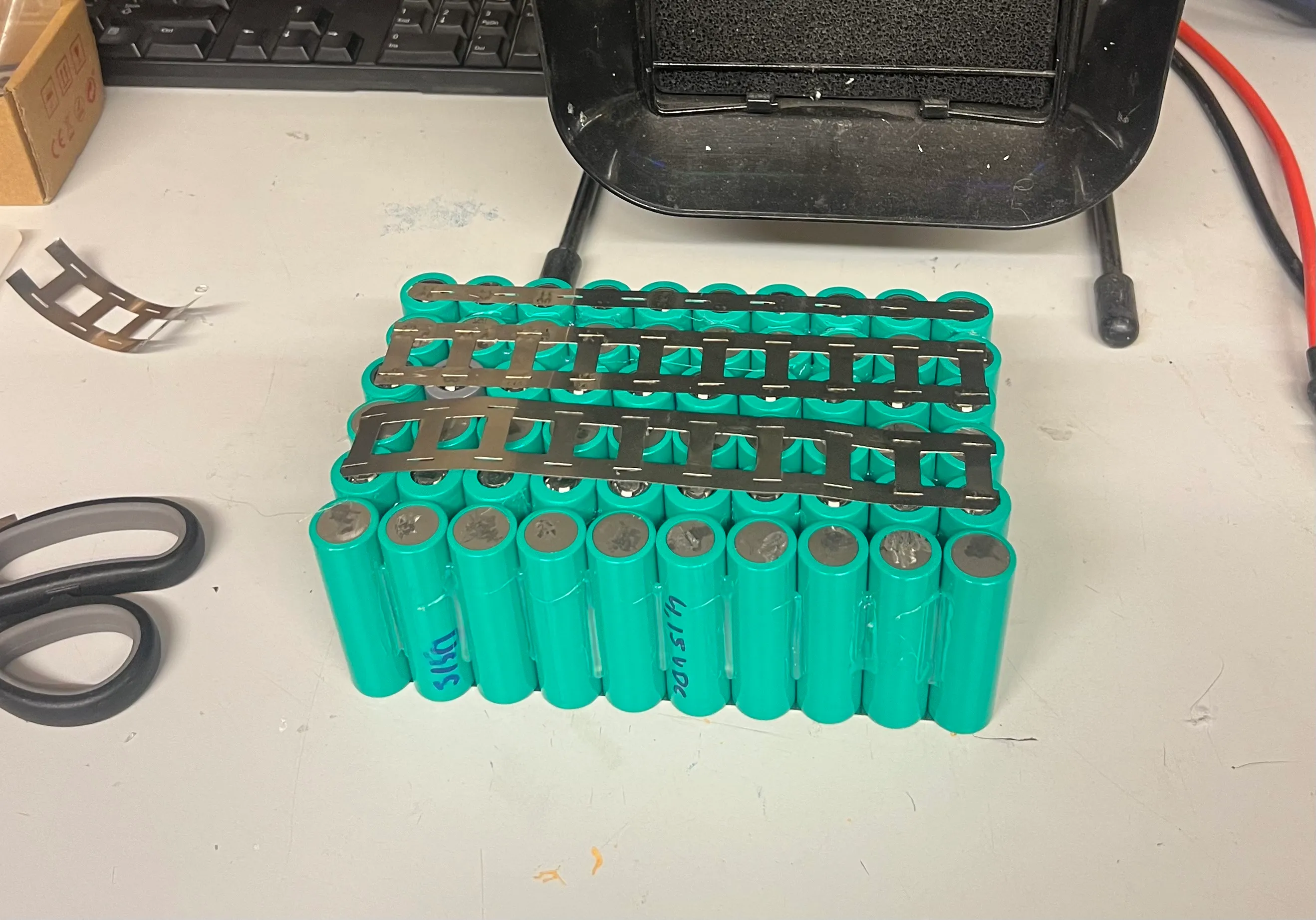 Cells laid out with nickel busbars, ready for spot welding.